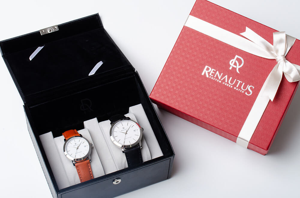 ペアボックスに入ったクオーツ式時計2本と白いリボンの赤いプレゼントボックス